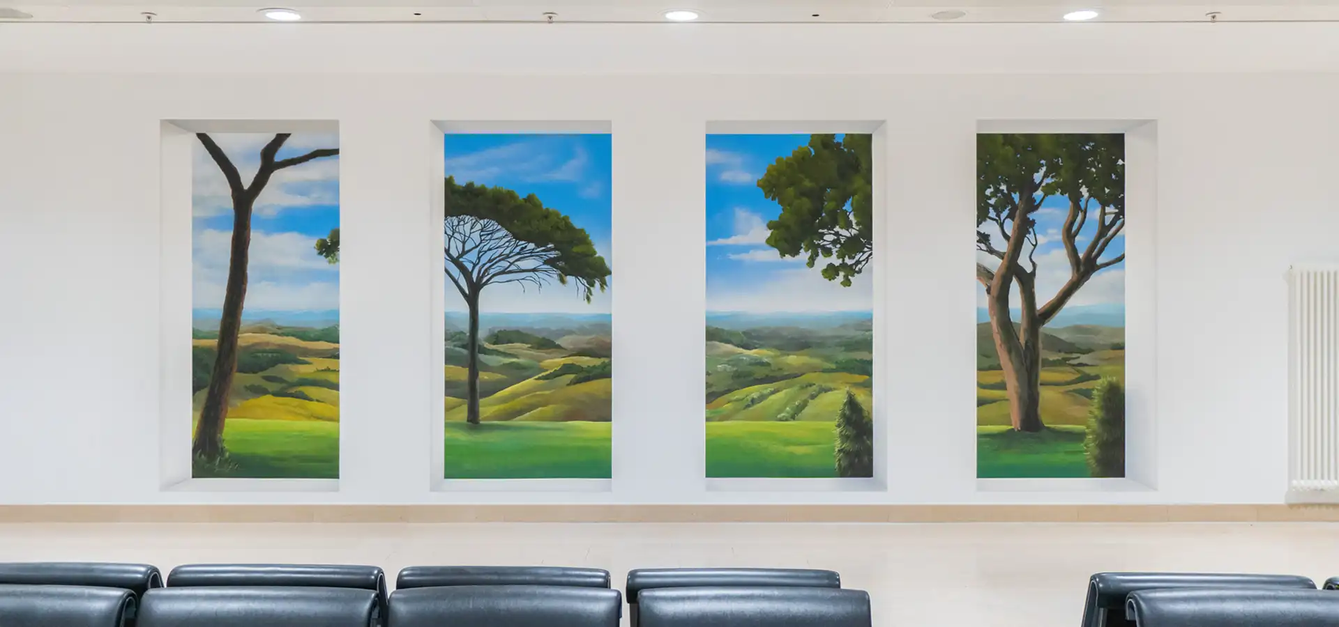 Großflächiges Wandbild mit einer Landschaftsszene in einem Wartebereich.
